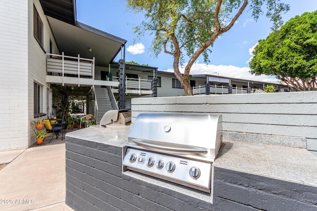 view of patio with area for grilling, an outdoor kitchen, stairway, and fence