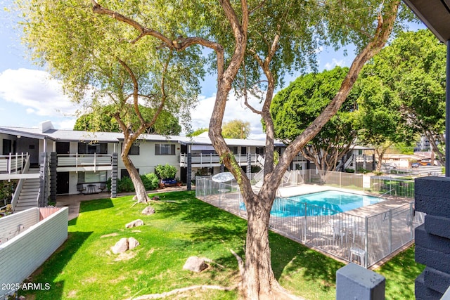 pool featuring stairs, a yard, and fence