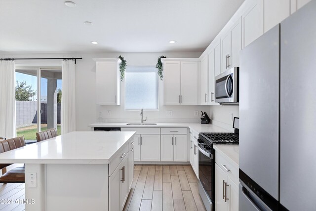 kitchen with stainless steel appliances, white cabinets, light hardwood / wood-style floors, and sink