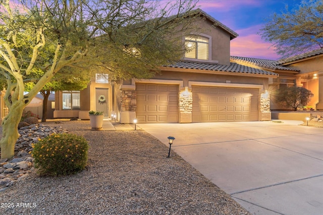 view of front facade featuring an attached garage, stucco siding, concrete driveway, stone siding, and a tiled roof