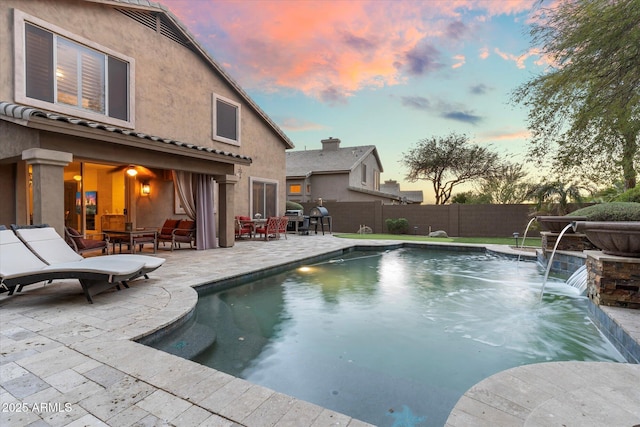 pool at dusk with a patio, a fenced backyard, and a fenced in pool