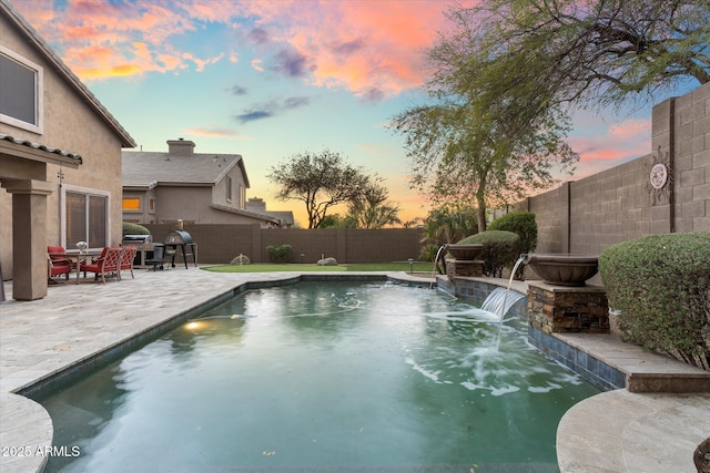 pool at dusk with a patio area, a fenced in pool, and a fenced backyard