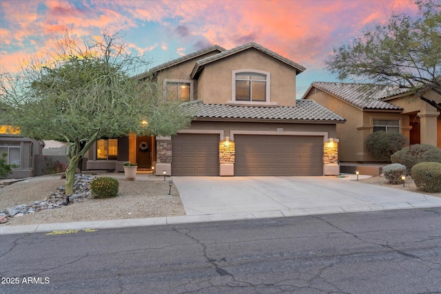 view of front of home with stucco siding, stone siding, a garage, and driveway