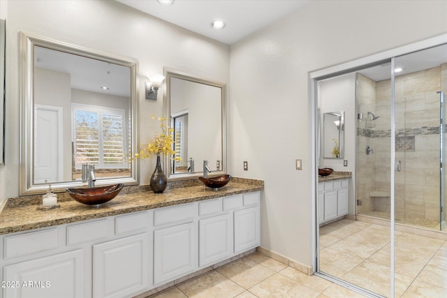 bathroom featuring a shower stall, double vanity, tile patterned floors, and a sink