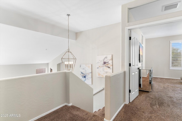 corridor with visible vents, carpet floors, vaulted ceiling, a notable chandelier, and an upstairs landing