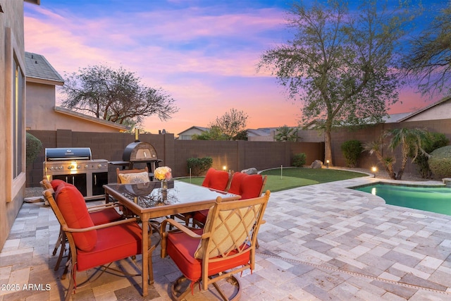 view of patio featuring grilling area, a fenced in pool, a fenced backyard, and outdoor dining space