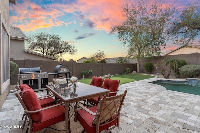 view of patio featuring outdoor dining space, a fenced in pool, a fenced backyard, and area for grilling