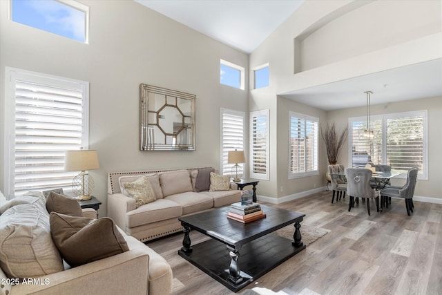 living room with baseboards, a high ceiling, and light wood-style floors