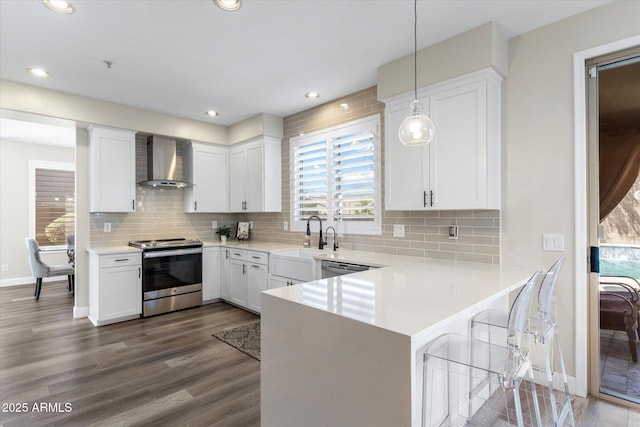 kitchen featuring wall chimney range hood, light countertops, electric stove, dark wood-style floors, and white cabinets