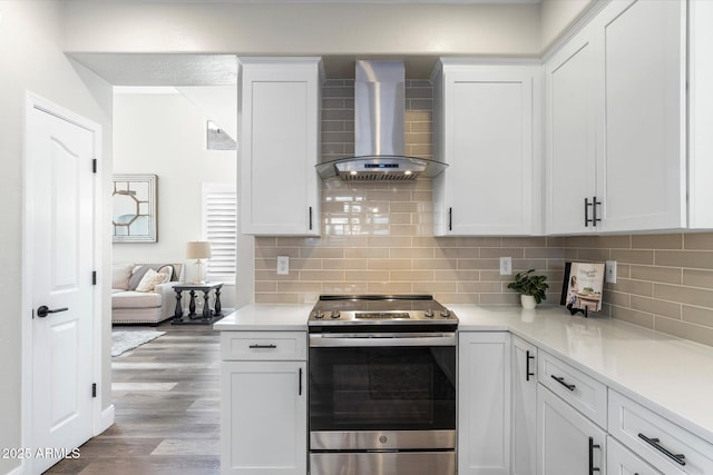 kitchen with tasteful backsplash, stainless steel electric range oven, wood finished floors, white cabinetry, and wall chimney exhaust hood