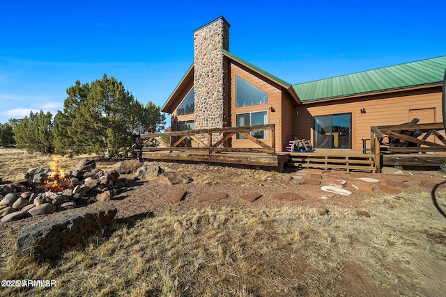 back of property with a deck, a chimney, and metal roof