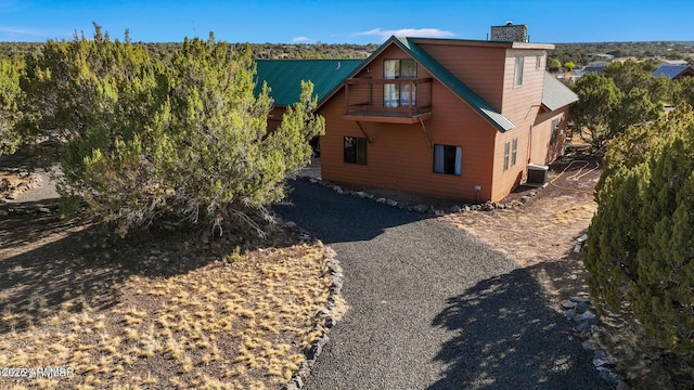 exterior space featuring central AC, metal roof, and a chimney