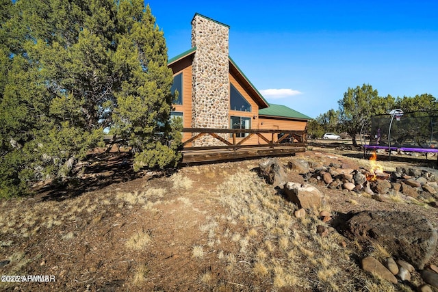 exterior space featuring a trampoline, a wooden deck, and a chimney