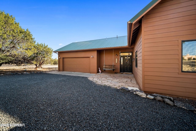view of side of home with an attached garage and metal roof