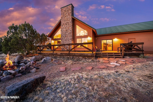 back of property with a wooden deck, metal roof, and a chimney