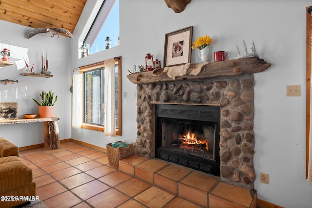 living area featuring baseboards, wooden ceiling, a stone fireplace, vaulted ceiling, and tile patterned floors