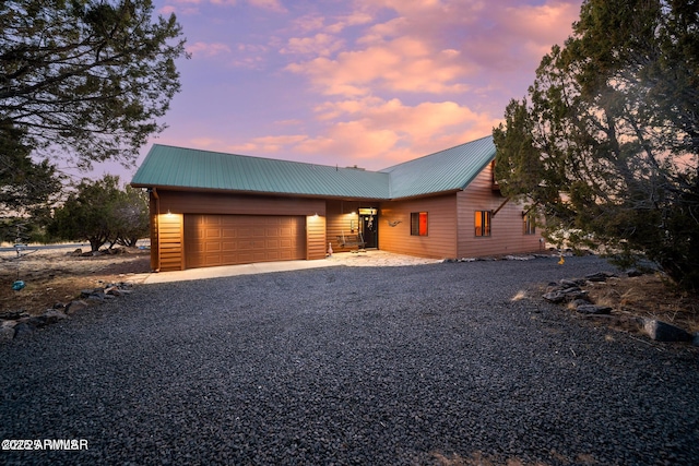 chalet / cabin with metal roof, a garage, and driveway