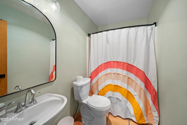 bathroom featuring toilet, a shower with shower curtain, and a sink