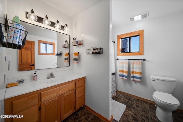 bathroom with toilet, vanity, baseboards, and visible vents
