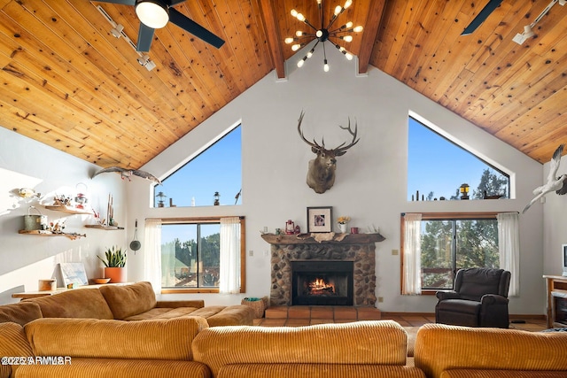 living room with ceiling fan with notable chandelier, high vaulted ceiling, a healthy amount of sunlight, and a fireplace