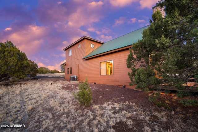 property exterior at dusk featuring metal roof and central AC