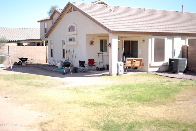 rear view of house featuring stucco siding, a lawn, fence, cooling unit, and a tiled roof