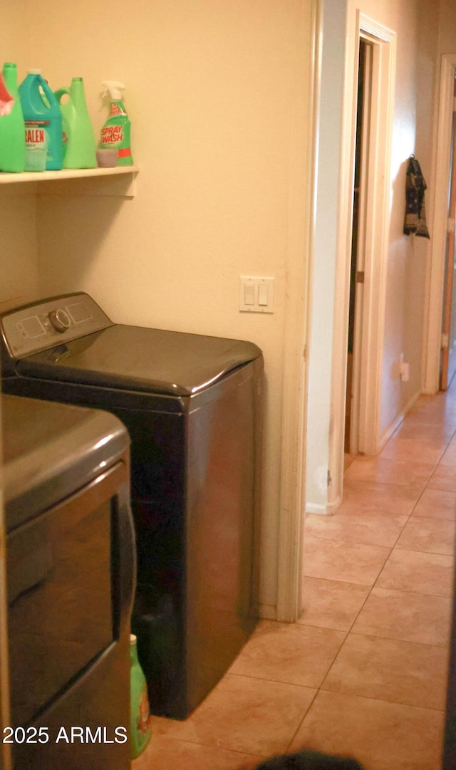 washroom with washer and clothes dryer, light tile patterned floors, and laundry area