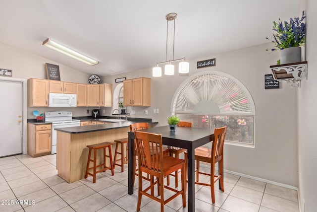 kitchen featuring white appliances, a kitchen breakfast bar, sink, kitchen peninsula, and vaulted ceiling