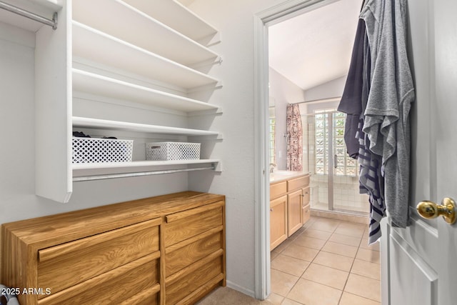 spacious closet featuring sink, vaulted ceiling, and light tile patterned floors