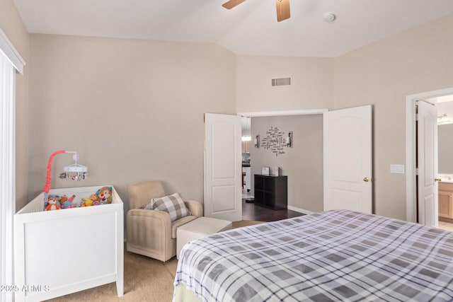 bedroom with ceiling fan, connected bathroom, carpet floors, and vaulted ceiling