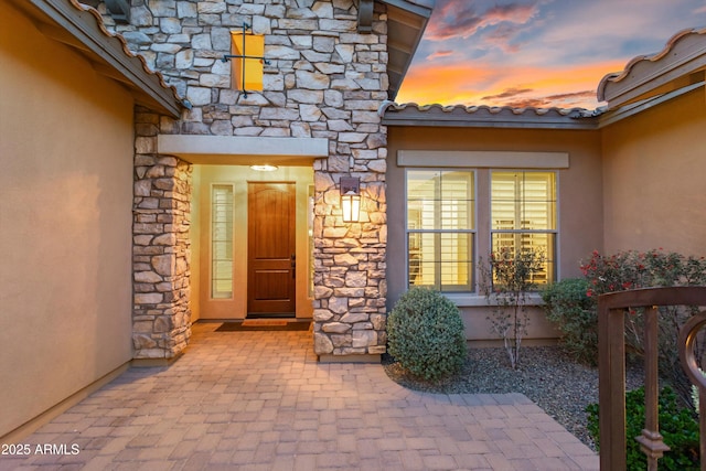 doorway to property with stucco siding and stone siding