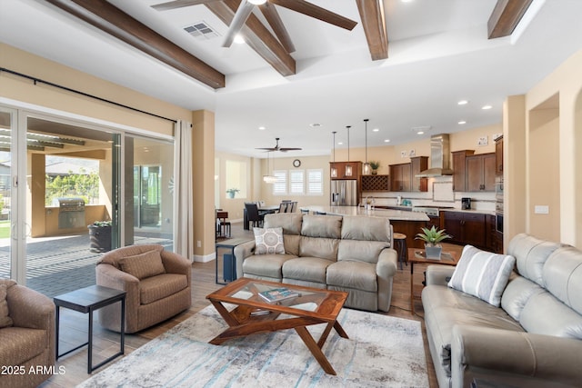 living room with ceiling fan, beamed ceiling, light wood-type flooring, visible vents, and recessed lighting