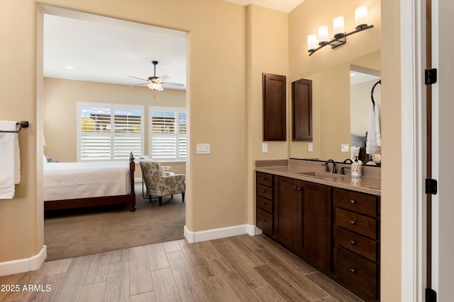ensuite bathroom featuring connected bathroom, vanity, a ceiling fan, wood finished floors, and baseboards