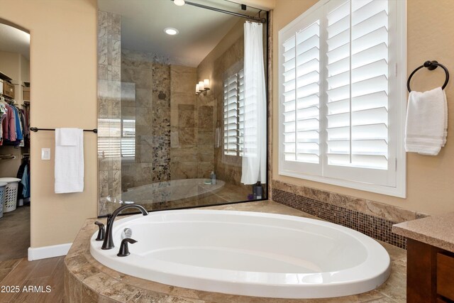 bathroom featuring a tile shower, a garden tub, a spacious closet, and plenty of natural light