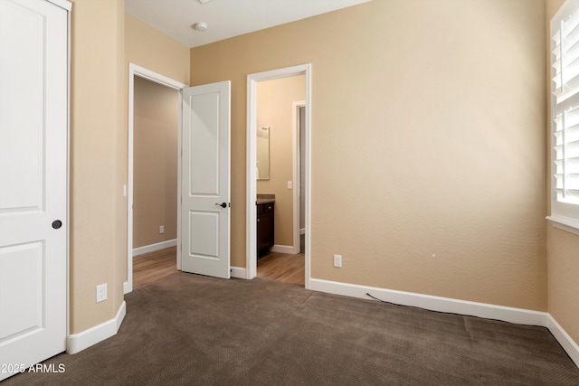 unfurnished bedroom with carpet flooring, baseboards, and connected bathroom