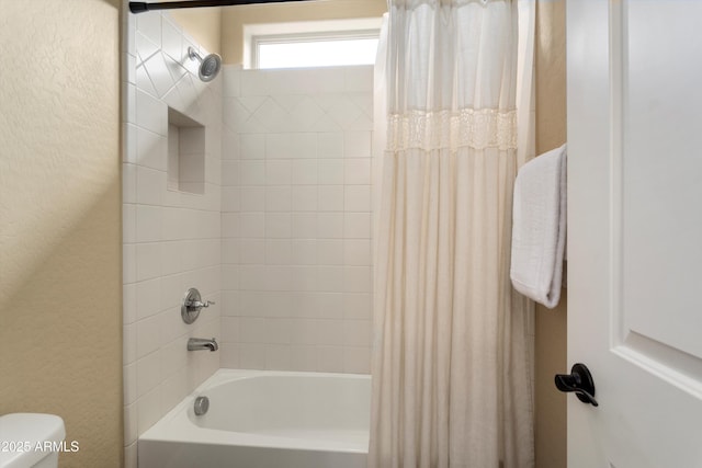 full bath featuring shower / bath combo, toilet, and a textured wall