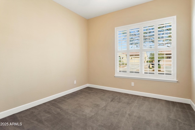 empty room featuring dark carpet and baseboards