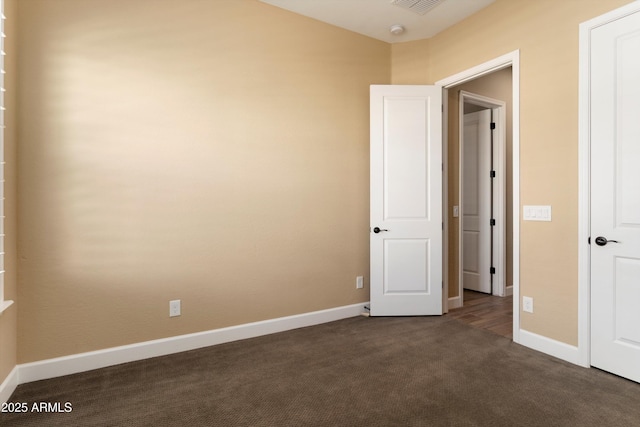 unfurnished bedroom with dark colored carpet, visible vents, and baseboards