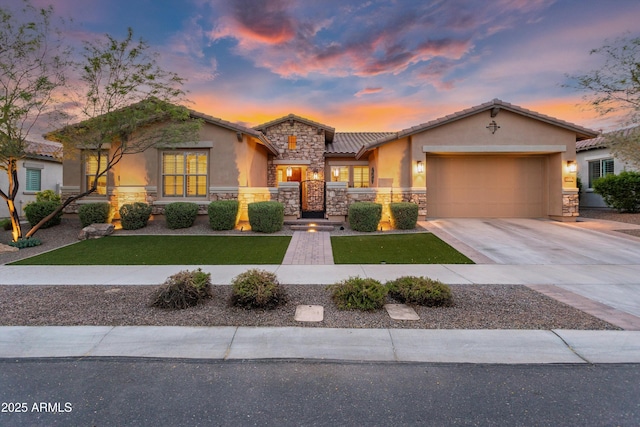 mediterranean / spanish home featuring an attached garage, a yard, stucco siding, and stone siding