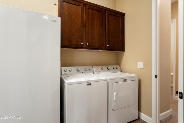 clothes washing area with washer and dryer, baseboards, cabinet space, and light wood-style flooring