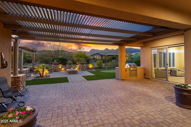 patio terrace at dusk featuring grilling area, a fenced backyard, and a pergola