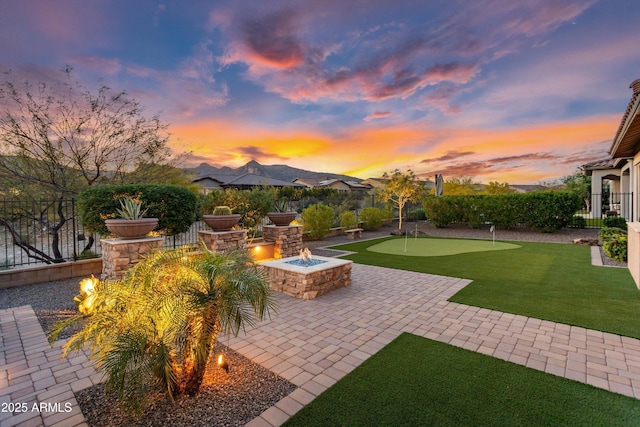 yard at dusk featuring an outdoor fire pit, a patio, and fence