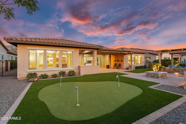 rear view of house with an outdoor fire pit, a tiled roof, a patio area, and stucco siding