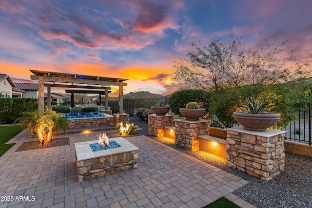 patio terrace at dusk with a fenced backyard, a fire pit, and a pergola