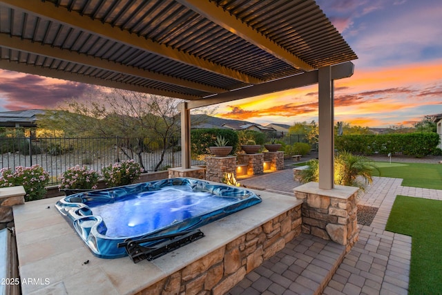 patio terrace at dusk with fence, an outdoor hot tub, and a pergola