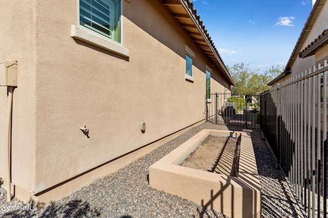 view of home's exterior featuring central AC, fence, and stucco siding