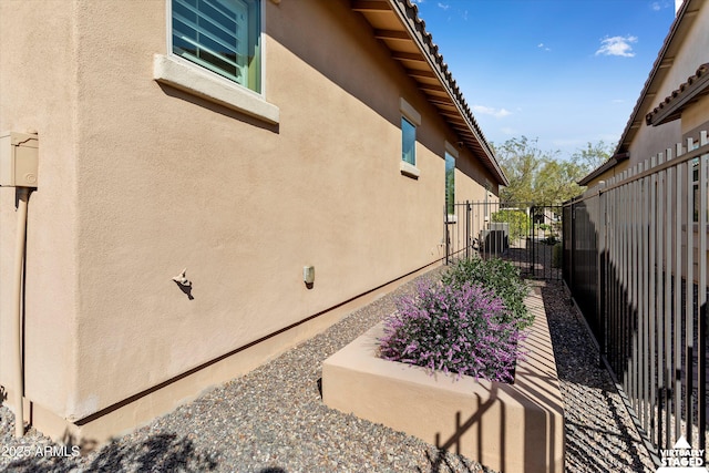 view of property exterior with stucco siding and fence
