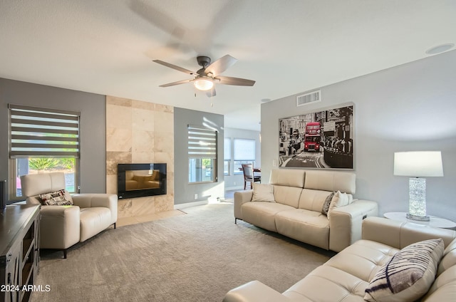 carpeted living room with a tiled fireplace, ceiling fan, and a healthy amount of sunlight