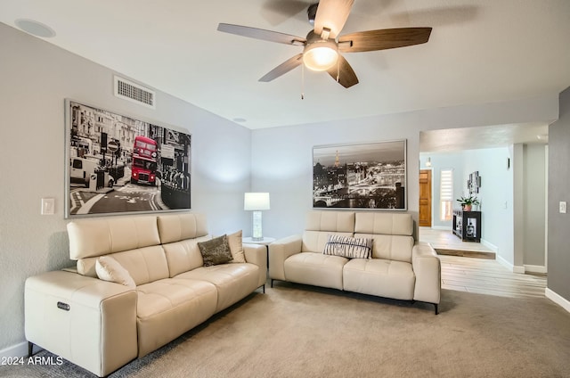 living room featuring a healthy amount of sunlight, ceiling fan, and light carpet