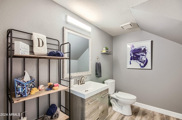 bathroom featuring vaulted ceiling, wood-type flooring, toilet, vanity, and a textured ceiling